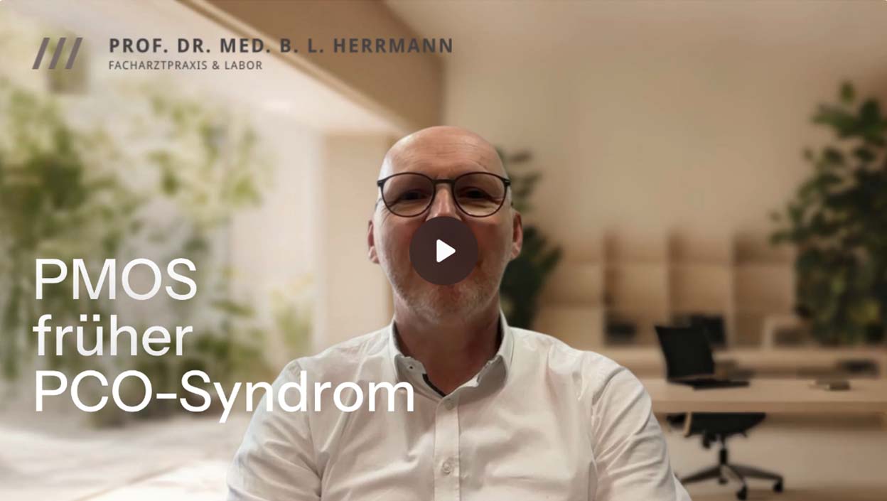 Prof. Dr. Herrmann und weißem Hemd, der in die Kamera blickt, mit einem Play-Button-Symbol auf dem Bild